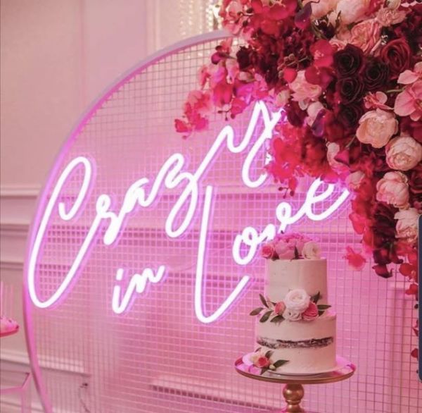 Crazy In Love Wedding Sign in brilliant LED neon flex shown in pink with wedding florals and cakes - photo from CustomNeon.com