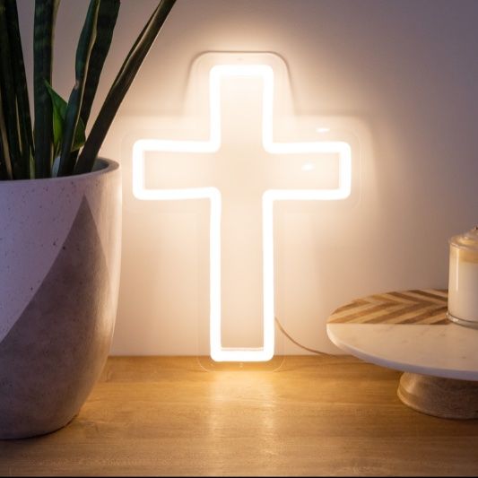 LED neon cross shown illuminated in white amongst other home decorations - photo from CustomNeon.co.uk