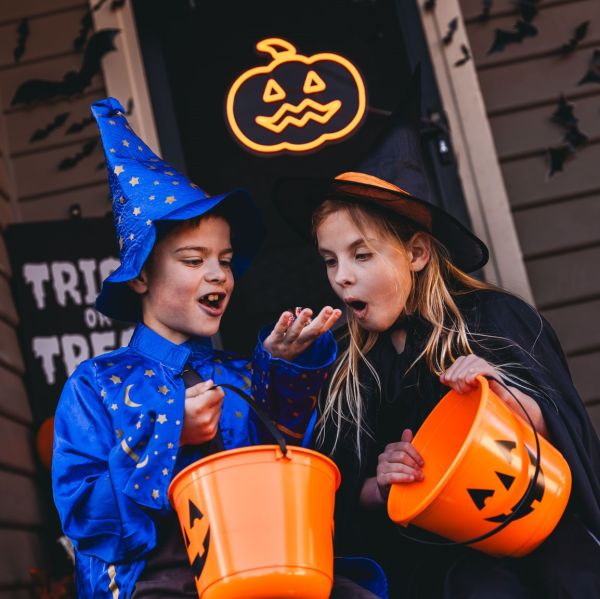 CUSTOM NEON® Spooky Jack O Lantern in pumpkin orange on a dark door surrounded by Halloween decorations