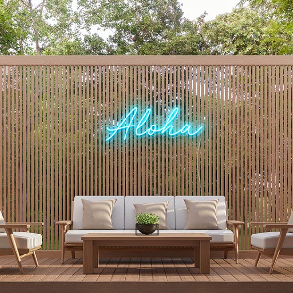 Custom Neon® Aloha sign in tropical blue on a wooden screen in an alfresco entertainment area.