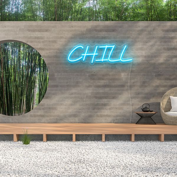 Custom Neon® Chill light sign in blue mounted to a brick wall in a zen garden setting