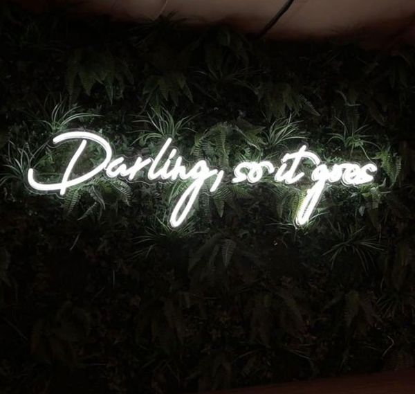 Darling, so it goes Neon Sign Quote for Weddings & Home Decor shown on green wall
 - photo from CustomNeon.co.uk