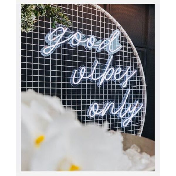 Good Vibes Only LED neon sign in 3 pieces shown on a mesh screen at an event - photo from CustomNeon.co.uk