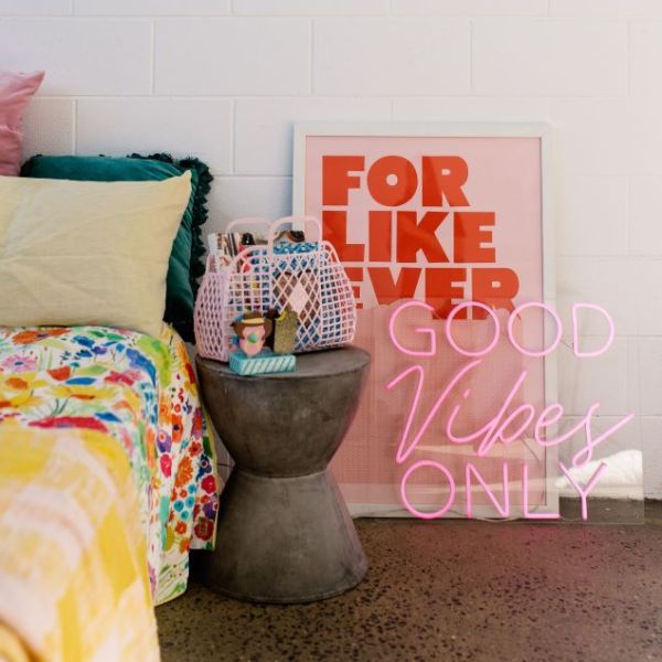 Good Vibes Only neon sign in pink with a pink jacket so it looks great both on and off - shown  in a bedroom - sign by CustomNeon.co.uk