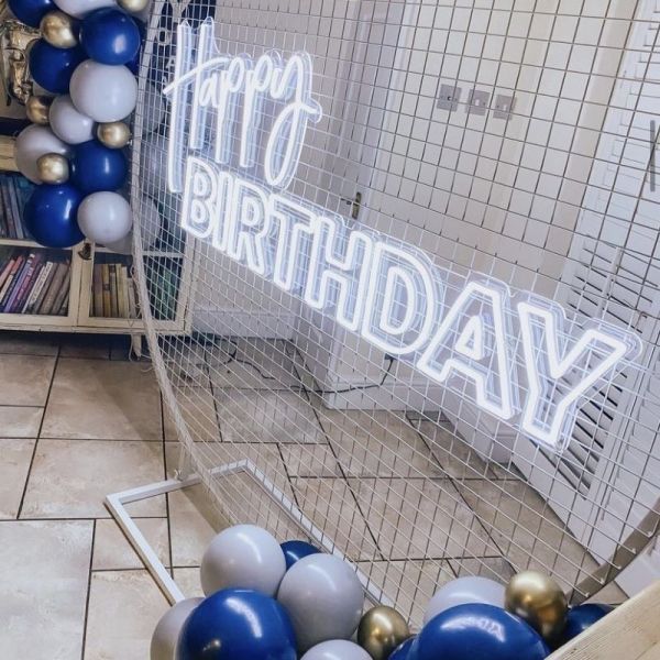 Custom Neon® Happy Birthday sign in white LED neon flex on an arched frame decorated with balloon garlands @raspberrycraftsandevents.