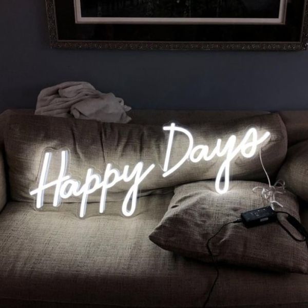 Happy Days LED neon sign shown illuminated on a couch - photo CustomNeon.co.uk