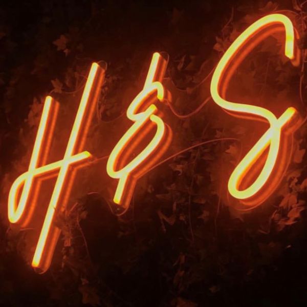 Bride & Groom Initials Neon Sign against a green wall at a wedding - photo Custom Neon®