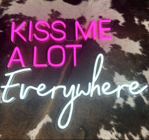Kiss Me A Lot Everywhere LED Neon Sign in pink and white shown on faux cow hide - photo CustomNeon.co.uk