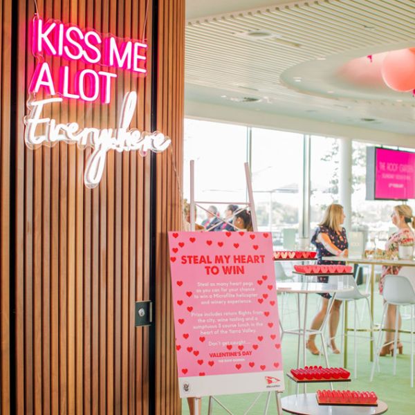 Kiss Me A Lot Everywhere LED Neon Sign shown hung from the entrance to a Valentine's Day event - photo CustomNeon.co.uk