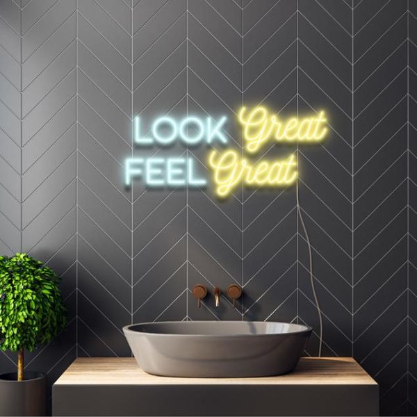 Look Great Feel Great CUSTOM NEON® pre-designed sign in mint green & yellow shown on a dark grey wall above a sink
