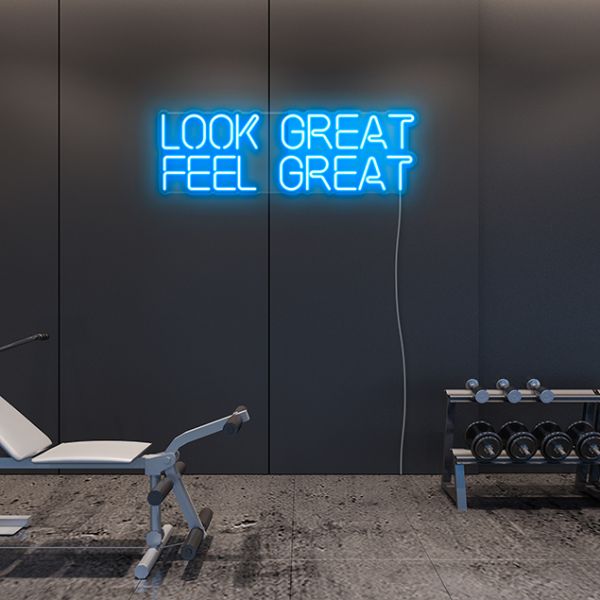 Look Great Feel Great CUSTOM NEON® sign shown in tropical blue on a dark fitness studio wall with gym equipment