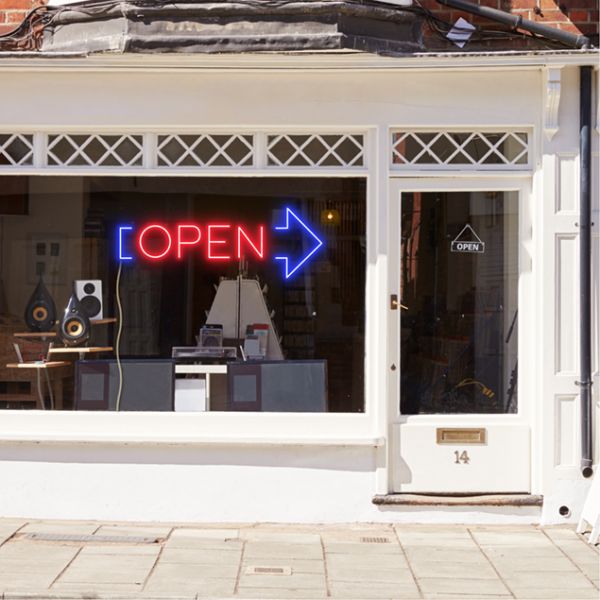 Neon light open sign in red with an oversized blue arrow shown in a shop window - from CustomNeon.co.uk