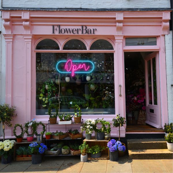 LED Neon Flex open sign in a modern script font surrounded by an oblong frame shown in a florist's shop window - from CustomNeon.co.uk