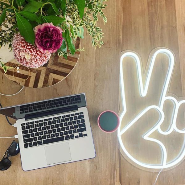 LED Neon Peace Emoji shown on wooden floor - Photo CustomNeon.co.uk