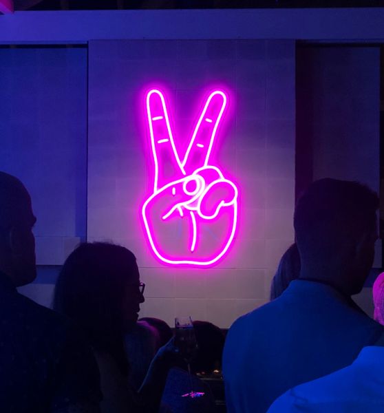 Neon Peace Sign neon light shown wall mounted in a busy restaurant
