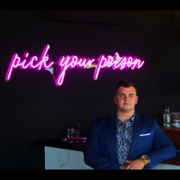 Pick Your Poison LED Neon Bar Sign shown above the bar at a party - from CustomNeon.co.uk