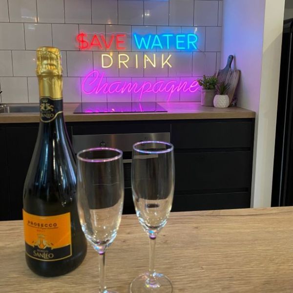Save Water Drink Champagne neon bar sign shown in a kitchen - from Custom Neon