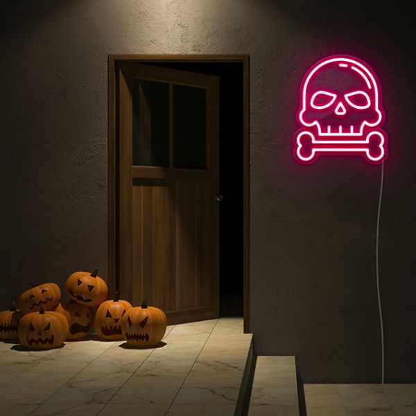 Skull & Bone pink light-up wall art from Custom Neon® shown on dark wall in Halloween setting