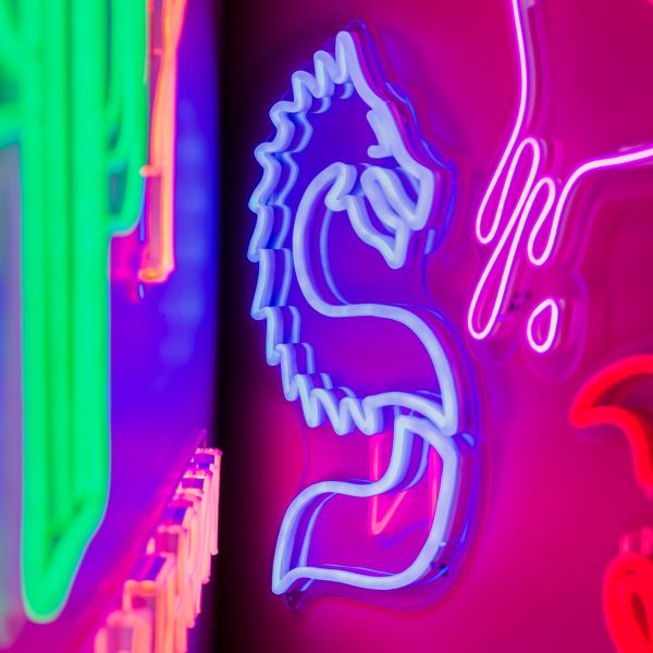Stylized Chinese Dragon LED neon art from Custom Neon® shown in blue styled on a dark pink background surrounded by neon lights