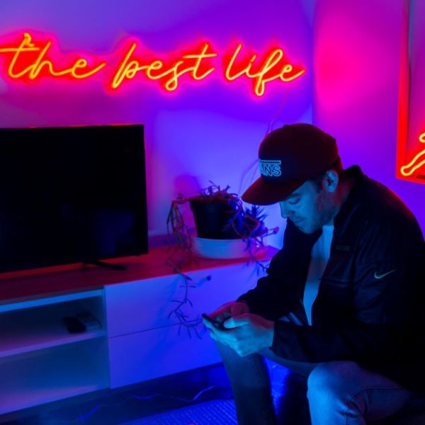 The Best Life red neon flex sign shown above a flatscreen TV in a living room @customneon