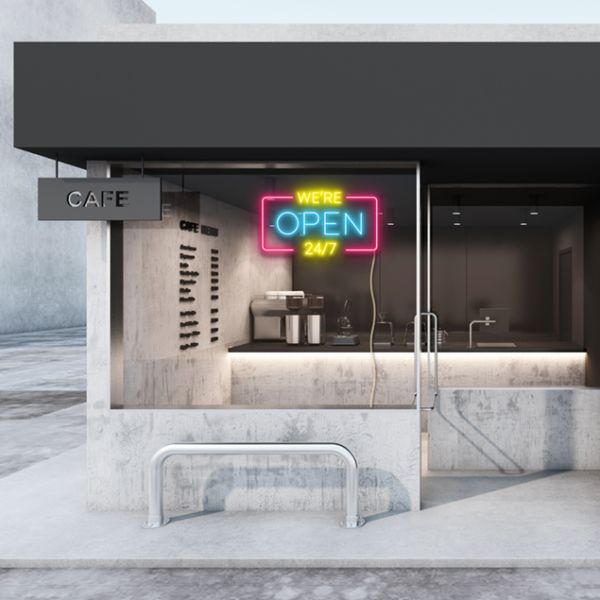 WE'RE OPEN 24/7 neon sign in yellow, blue & pink shown in a cafe window - from CustomNeon.com.au