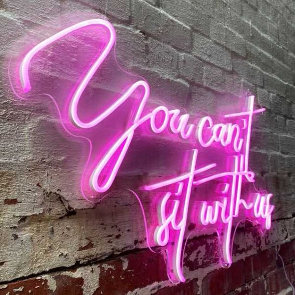 You Can't Sit with Us faux neon sign on a brick wall from Custom Neon