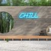 Custom Neon® Chill light sign in blue mounted to a brick wall in a zen garden setting