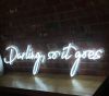Beautiful cursive neon word sign * Darling, so it goes * shown against exposed brick wall
 - photo from CustomNeon.co.uk