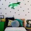 Personalised LED neon child's name sign with dinosaur background shown in child's bedroom- from CustomNeon.co.uk