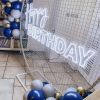 Custom Neon® Happy Birthday sign in white LED neon flex on an arched frame decorated with balloon garlands @raspberrycraftsandevents.