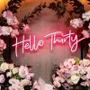 Hello Thirty Light Up Birthday Sign in pink surrounded by floral decorations - photo from CustomNeon.co.uk