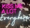 Kiss Me A Lot Everywhere LED Neon Sign in pink and white shown on faux cow hide - photo CustomNeon.co.uk