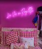 La Vie En Rose pink neon sign on dark pink wall above a bed - from Custom Neon