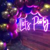 Let's Party portable LED neon sign shown on a wire mesh background surrounded by balloons - photo from CustomNeon.co.uk