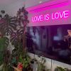 Custom Neon® pink LOVE IS LOVE light sign shown wall mounted above a TV in a living room,Custom Neon® signs and artwork mounted above a bed,LED neon bedroom signs by Custom Neon®