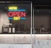 WE'RE OPEN 24/7 in brilliant yellow and red, with bright blue lines shown in a cafe window - from CustomNeon.co.uk