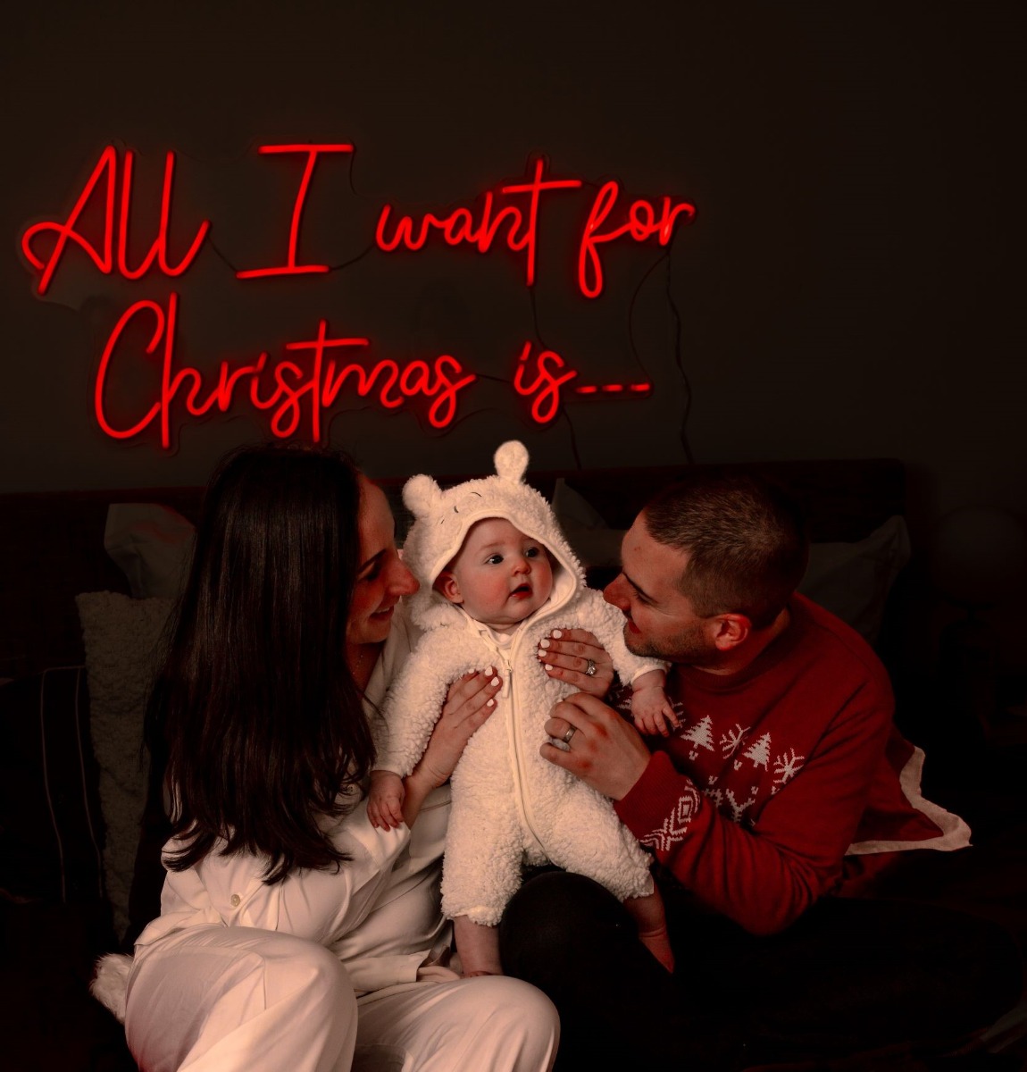 Custom Neon® red All I Want for Christmas... sign above a bed behind a family