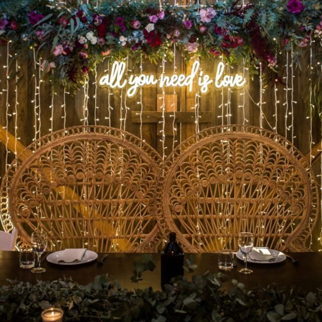 All You Need is Love warm white Custom Neon® sign behind the bride and groom's place at the top table with string lights in the background