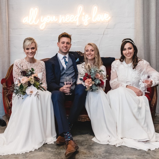 All You Need is Love Custom Neon® sign backdrop on a white wedding photo wall