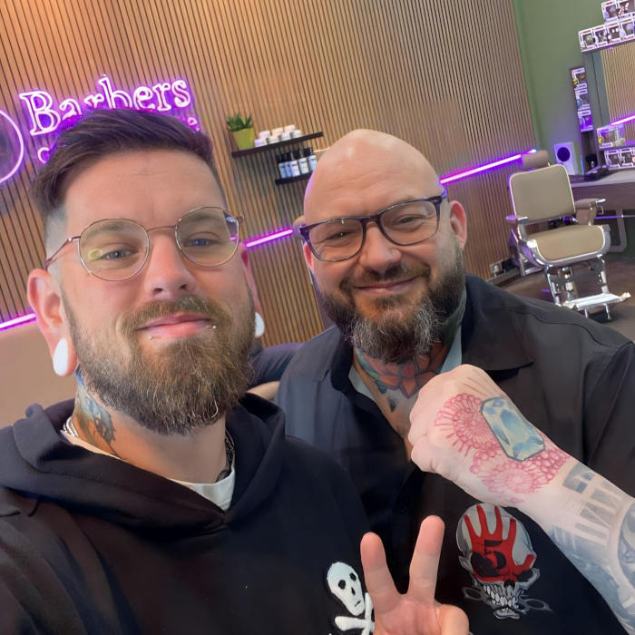 Staff selfie with a barbershop logo sign by Custom Neon® in the background  @barbers.onthesquare
