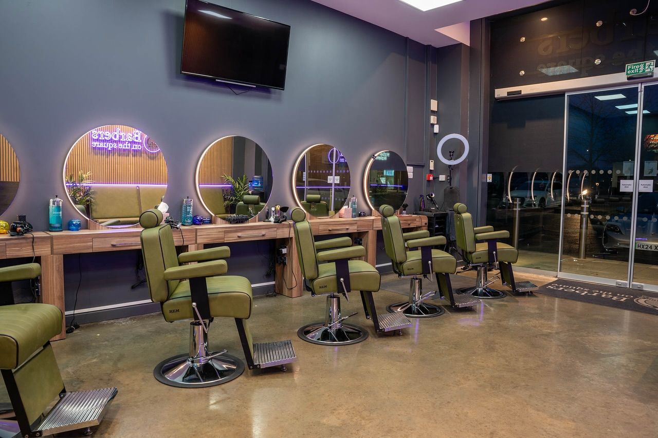 Barbers on the Square purple Custom Neon® sign reflected in the mirrors of the barber shop