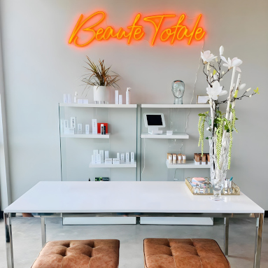Orange  Custom Neon® business sign installed on a white wall @beautetotale