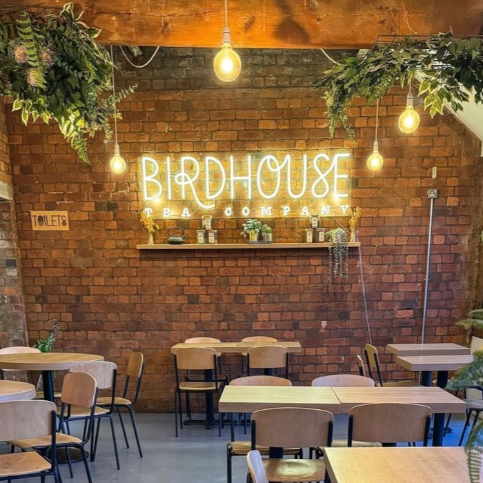 Warm white Custom Neon® logo sign on a brick wall @birdhouseteacompany