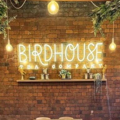 Warm white Custom Neon® logo sign on a brick wall @birdhouseteacompany