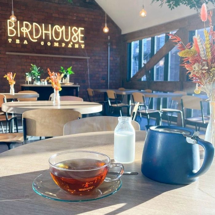 Birdhouse Tea Company Custom Neon® logo on a large red brick wall inside the @birdhouseteacompany cafe