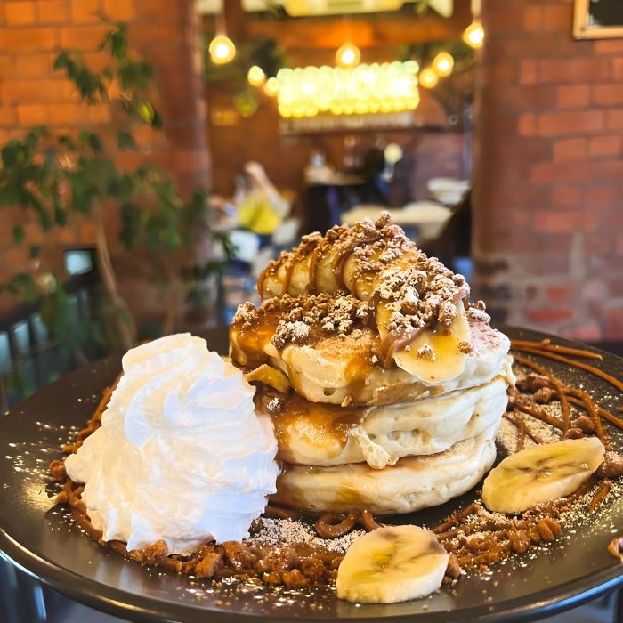 Pancakes on a plate with a warm white Custom Neon® business name sign in the background @birdhouseteacompany