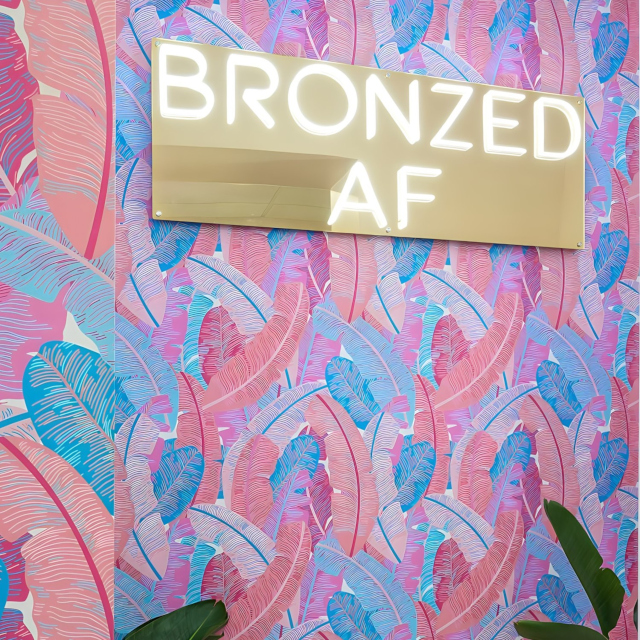 Bronzed AF white LED Custom Neon® sign on gold acrylic backboard mounted on colourful wallpaper @winkd_lash