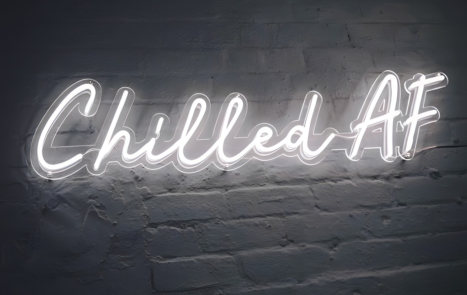 Chilled AF white Custom Neon® quote sign on dark brick wall @barbertherapy