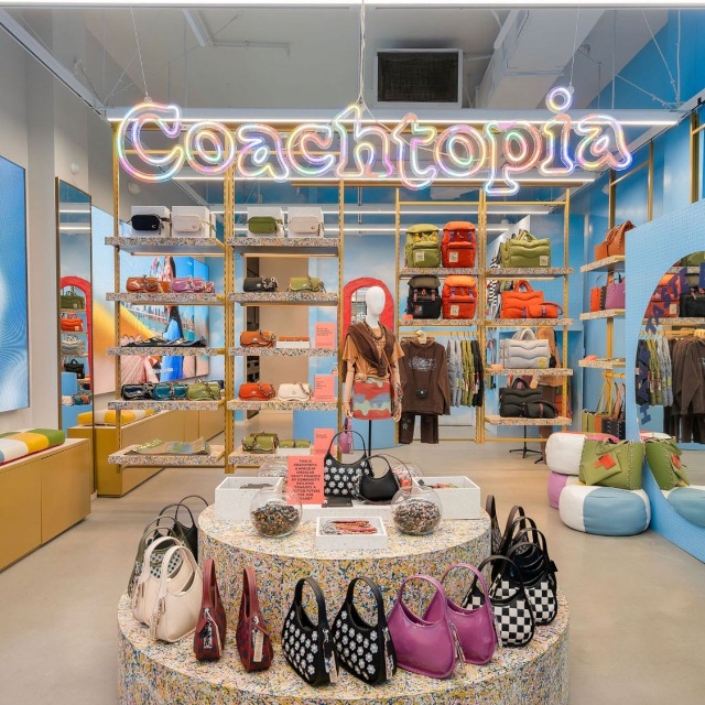 Custom Neon® colourful @coachtopia retail logo sign suspended from the ceiling above the merchandise displays
