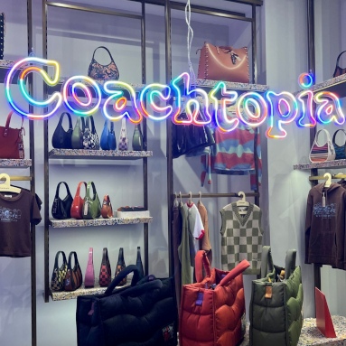Custom Neon® colorful @coachtopia logo hanging above the merchandise in a @coach store